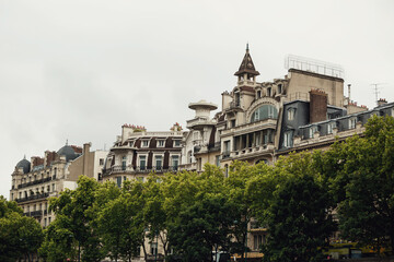 Fototapeta na wymiar Green trees before tall buildings in Paris
