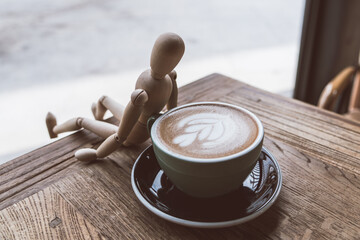 Hot mocha coffee or capuchino in the green cup lean by wood man on the wooden table