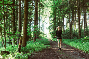 Woman running through forest in black clothes