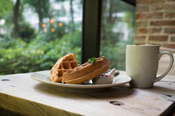 2 pieces of waffle with a white cup of coffee on the wooden table
