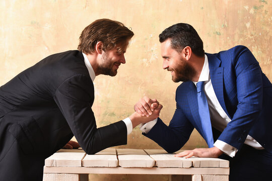 Business partners arm wrestling in office, success concept