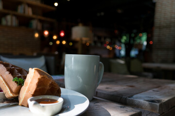 2 pieces of waffle with a white cup of coffee on the wooden table