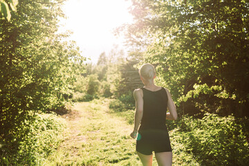 Woman running into the sunset in forest