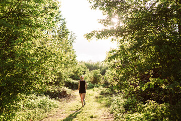 Woman running into the sunset in forest