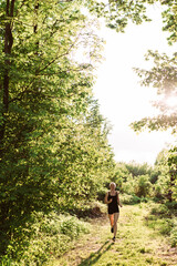 Woman running into the sunset in forest