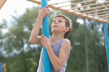 A teenager in a T-shirt climbs on a gymnastic pole