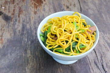 noodles with pork and vegetables on wooden table