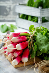 Bunch of fresh raw ripe young radishes with leaves on a light background. Selective focus. © kasia2003
