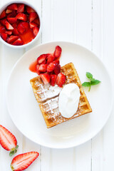 Pets (Belgian) waffles with strawberries and whipped cream.