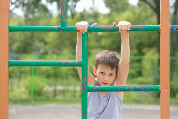 Fototapeta premium A teenager in a T-shirt is engaged in gymnastics on a horizontal bar