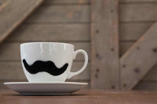 White coffee cup with black mustache on table