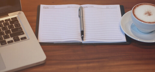 At the Desk with a cup of coffee. Notebook, pen and notebook computers.