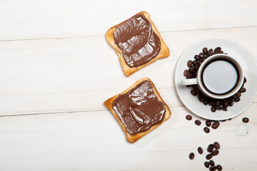 cup of coffee and toast with chocolate on a white wooden table