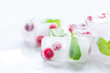 Ice cubes with berries and mint for summer drink on white background