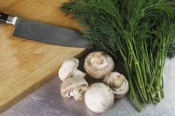 Mushrooms and dill on a cutting board before cutting