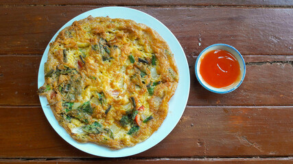 Omelette with herbal vegetables and chili sauce .