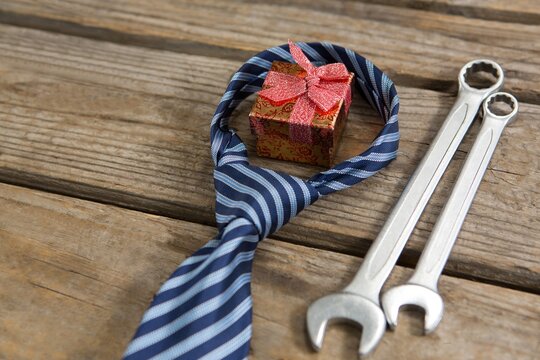 High Angle View Of Gift Box With Necktie And Work Tools