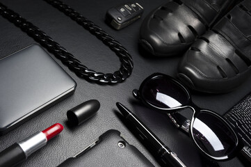 Woman accessories in business style, red lipstick, gadgets, jewelry, car key, sunglasses, shoes, and other luxury businesswoman attributes on leather black background, fashion industry 