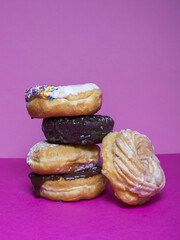 Stack of assorted donuts with pink background