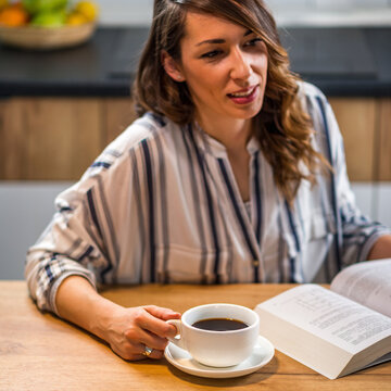 Woman drinking coffee and reading book