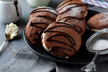 Chocolate cookies of  Woopie  Cookie with mascarpone cream on a gray dark concrete background. Selective focus. Top view. Space for text.