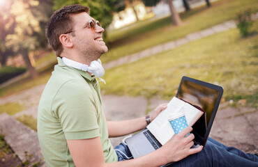 Fototapeta premium Young man with a laptop on a coffee break in the park. Lifestyle, education, technology