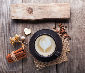 cup of cappuccino coffee on old vintage wooden table, dry flower , cinnamon, top view