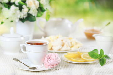 Obraz na płótnie Canvas Cup of tea with pink marshmallow and lemon