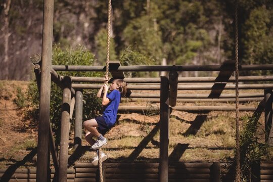 Determined girl climbing rope during obstacle course