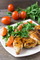 Spicy grilled chicken wings and vegetables  on rustic background.