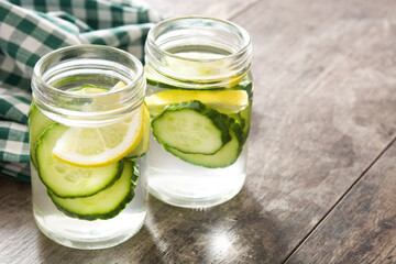 Detox water with cucumber and lemon on wooden table
