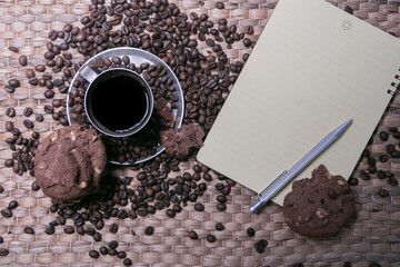 coffee cup and coffee beans on wooden table with cookies and notepad