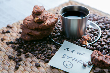 coffee cup and coffee beans on wooden table with cookies and notepad with message on the sticker
