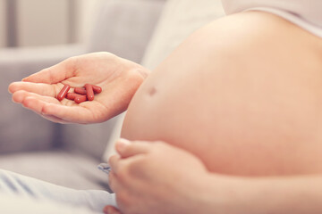 Pregnant woman holding pills at home