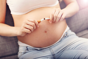 Close up of pregnant woman breaking cigarette