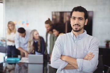 Portrait of young businessman standing with arms crossed