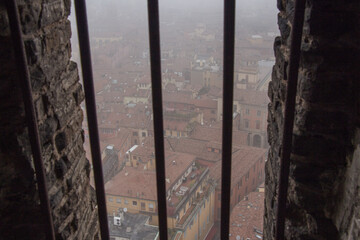 Typical red roofs of Bologna in a foggy day. View from a narrow window of Asinelli Tower. Emilia Romagna , Italy.