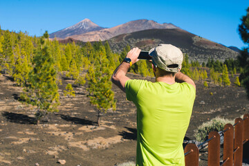 Fototapeta na wymiar A tourist takes pictures of a volcano in the Canary Islands