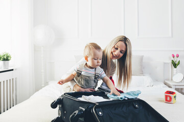 Travelling with kids. Happy mother with her child packing clothes for holiday