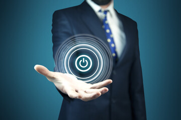 Businessman on blurred background holding render power button with his hand
