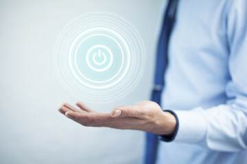Businessman on blurred background holding render power button with his hand
