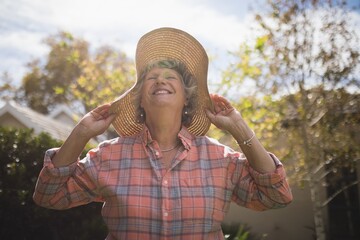 Smiling senior woman wearing sun hat on sunny day