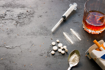 Alcohol in a glass, drugs, syringe, pack of cigarettes on a black background with space for text. Concept of bad habits
