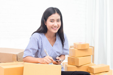 Young asian woman business owner work and white down address for deliver at home, woman business owner concept, 20-25 year old..