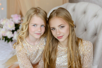 Two beautiful girls in a studio. They wear light beautiful dresses. Both are blond.
