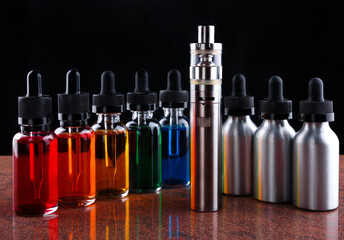 Electronic cigarette and bottles with vape liquid on granite surface and black background