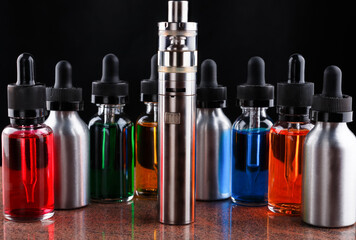 Electronic cigarette and bottles with vape liquid on granite surface and black background