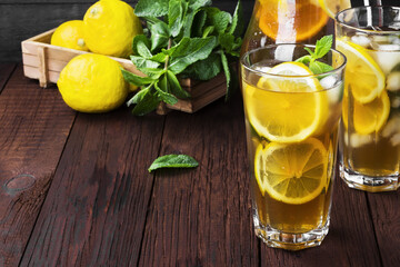 Ice tea with lemon and mint on a wooden background. Copy space. Food background. Toning