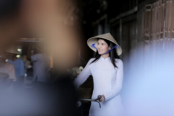 Beautiful women wearing Ao Dai dress traditional Vietnamese Cycling smile happily