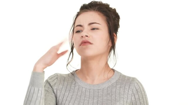 Young Caucasian girl with brunette hair standing on white background and smelling something bad in air in slowmotion